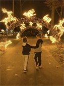 Two children stoll under a lighted arch way at the Light Garden in City Park. 